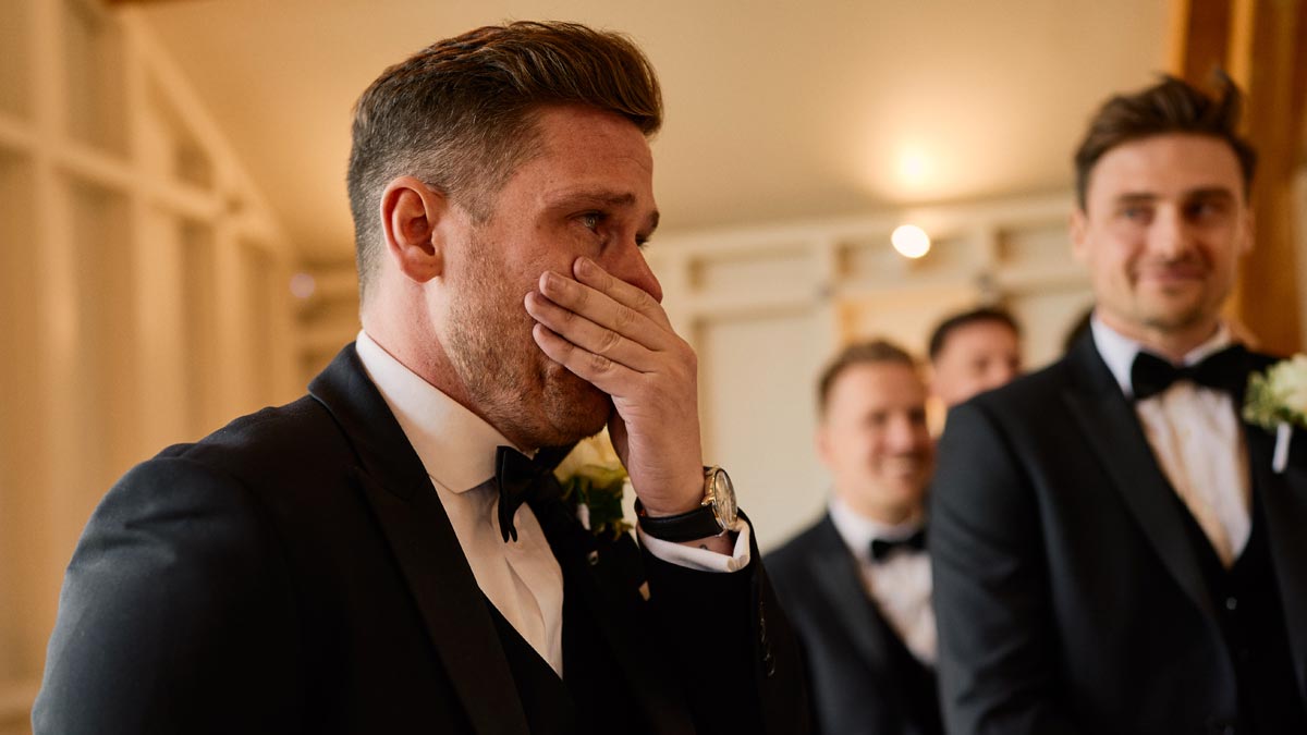 groom fighting back tears as his bride walks down the isle
