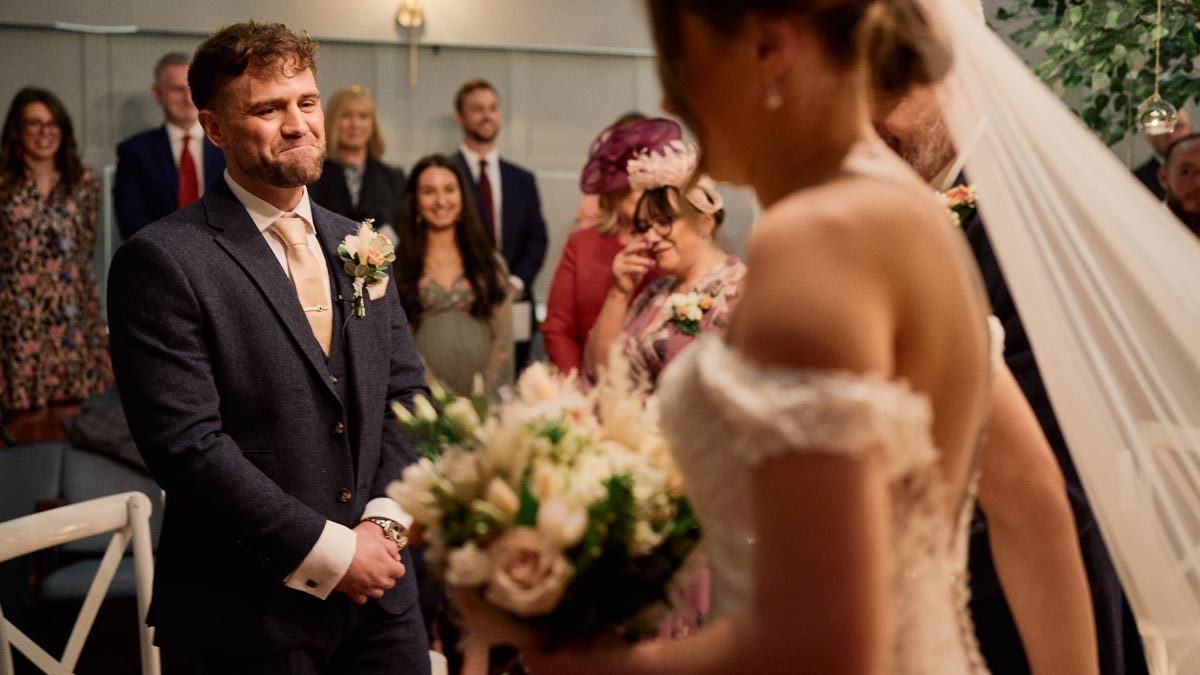 groom looking emotional as bride walks down the aisle